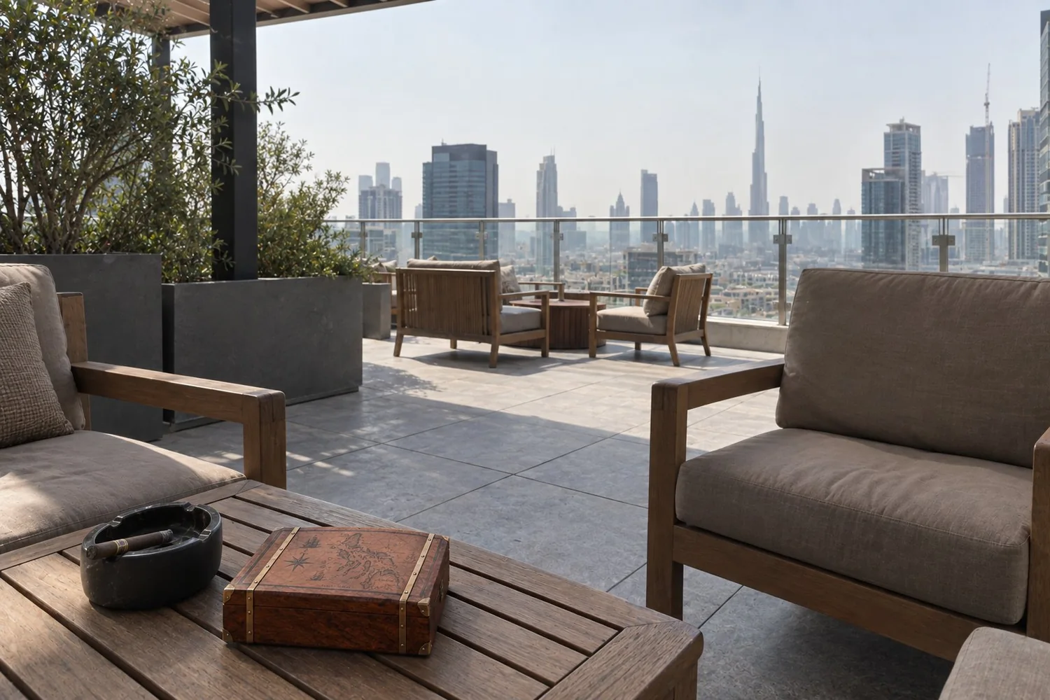 A rooftop terrace in Dubai: wooden armchairs, a cigar box on the table, the skyline behind